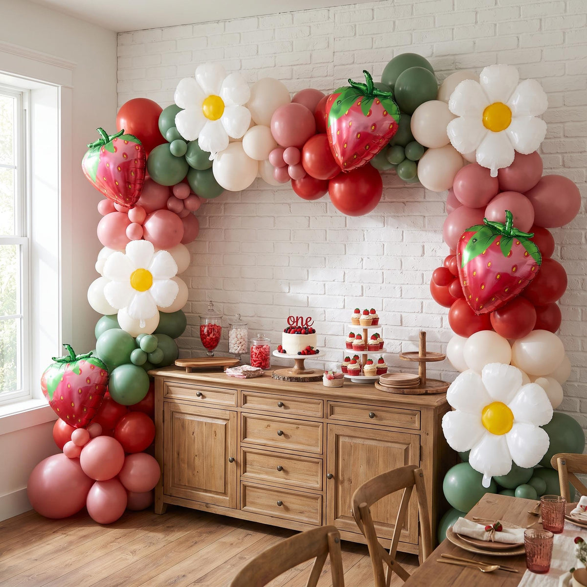 Berry First Birthday balloon garland installed on a wall at home