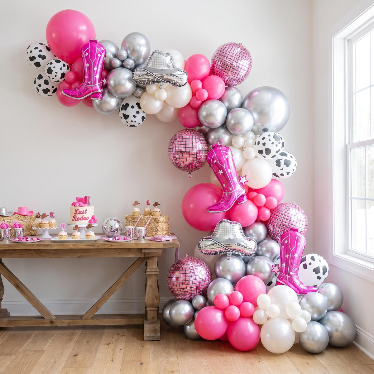 Disco Cowgirl (Last Rodeo) balloon garland installed on a wall at home